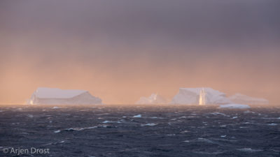 Tabular icebergs in a storm at sunset